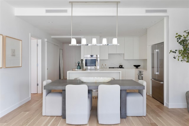 kitchen featuring modern cabinets, visible vents, high end fridge, and a center island with sink