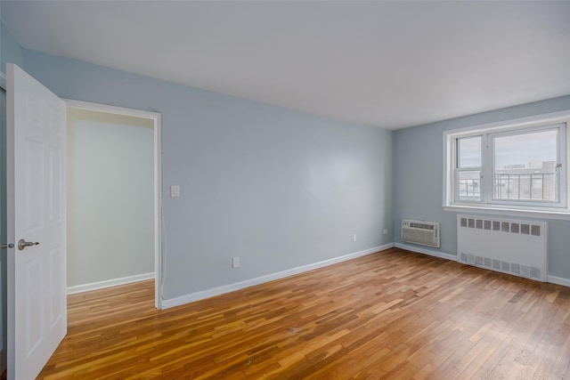 88-25 155th Ave Unit 6L, Howard Beach, NY 11414 - spare room featuring light wood-style flooring, an AC wall unit, radiator heating unit, and baseboards
