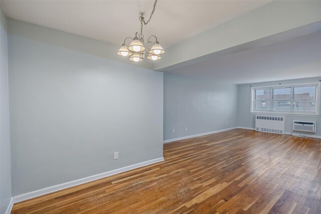88-25 155th Ave Unit 6L, Howard Beach, NY 11414 - unfurnished room featuring radiator, baseboards, a chandelier, an AC wall unit, and hardwood / wood-style floors