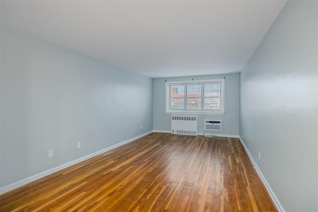 88-25 155th Ave Unit 6L, Howard Beach, NY 11414 - spare room featuring radiator, baseboards, a wall unit AC, and hardwood / wood-style floors