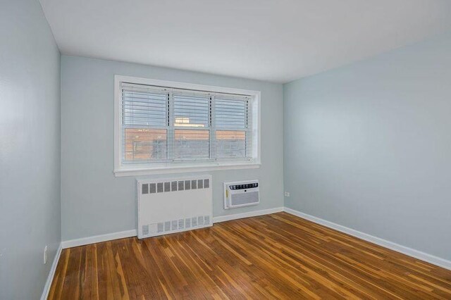 88-25 155th Ave Unit 6L, Howard Beach, NY 11414 - empty room featuring baseboards, an AC wall unit, wood finished floors, and radiator heating unit