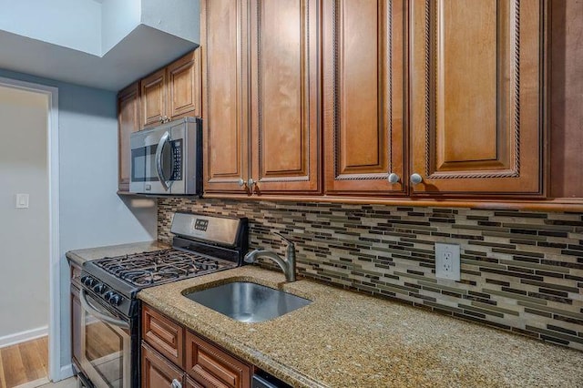 88-25 155th Ave Unit 6L, Howard Beach, NY 11414 - kitchen with light stone countertops, a sink, appliances with stainless steel finishes, brown cabinets, and backsplash