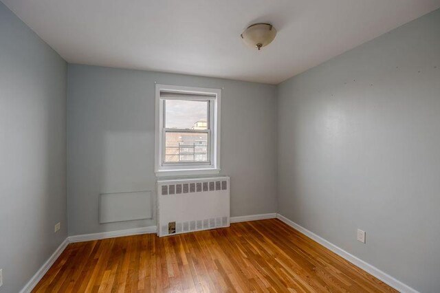 88-25 155th Ave Unit 6L, Howard Beach, NY 11414 - unfurnished room with radiator, wood finished floors, and baseboards