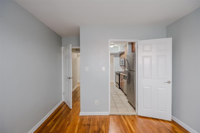 88-25 155th Ave Unit 6L, Howard Beach, NY 11414 - unfurnished bedroom with baseboards, light wood-style floors, and freestanding refrigerator