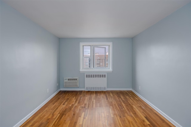 88-25 155th Ave Unit 6L, Howard Beach, NY 11414 - spare room featuring radiator, baseboards, wood-type flooring, and a wall mounted AC