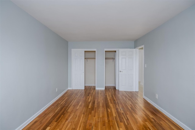 88-25 155th Ave Unit 6L, Howard Beach, NY 11414 - unfurnished bedroom with wood finished floors, multiple closets, and baseboards