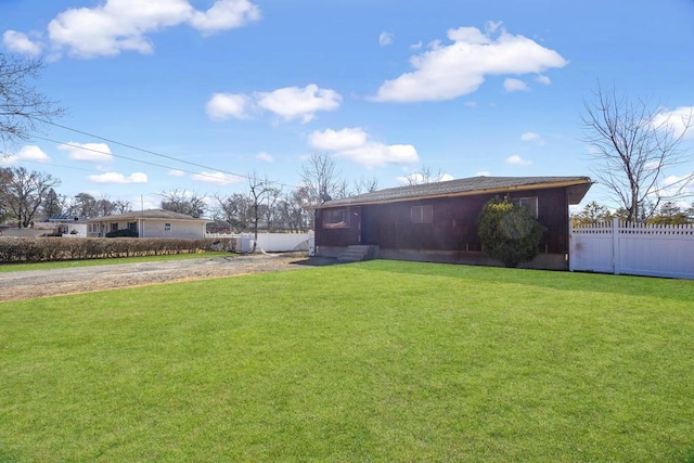 view of yard with driveway and fence