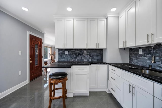 kitchen featuring baseboards, backsplash, recessed lighting, and white cabinetry