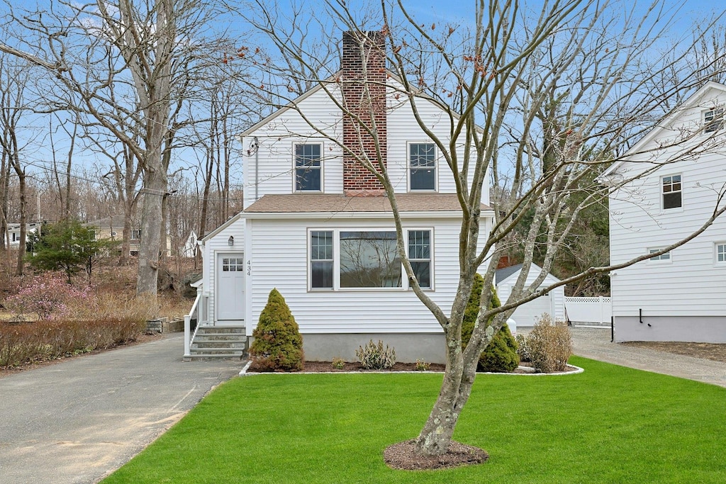 view of front facade with a chimney, a front lawn, and entry steps