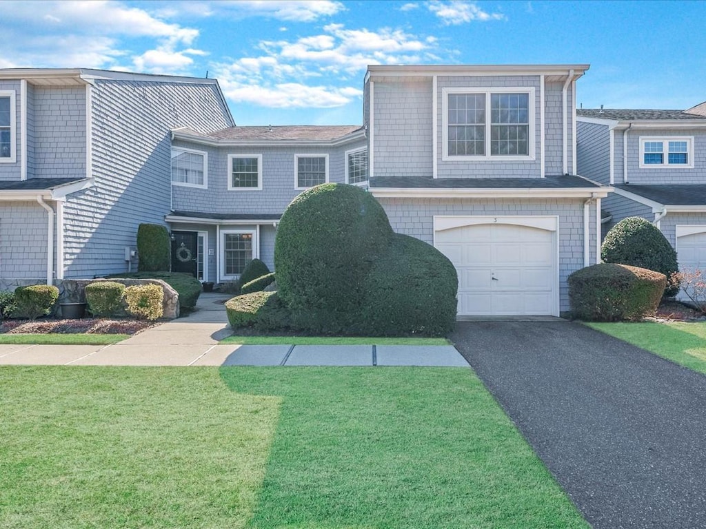 view of front of house with aphalt driveway, an attached garage, and a front lawn