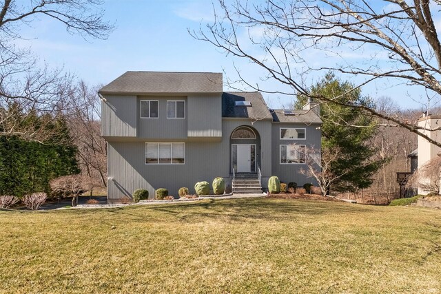 split level home with roof with shingles and a front yard