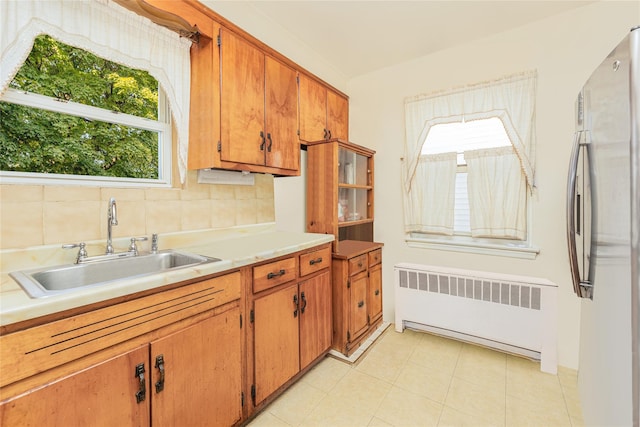 3476 Bruner Ave, Bronx, NY 10469 - kitchen featuring brown cabinetry, freestanding refrigerator, radiator heating unit, light countertops, and a sink