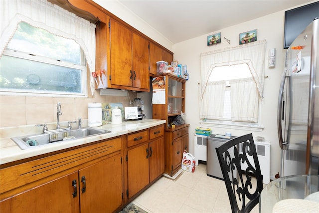 3476 Bruner Ave, Bronx, NY 10469 - kitchen featuring brown cabinetry, freestanding refrigerator, light countertops, a sink, and a wealth of natural light