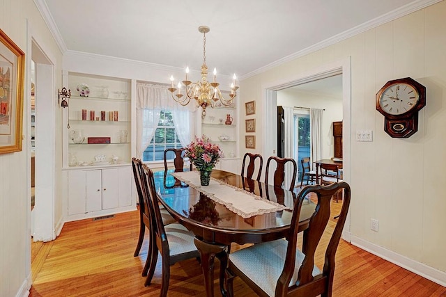 28 Rose Ave, Great Neck, NY 11021 - dining room featuring a chandelier, light wood finished floors, ornamental molding, built in shelves, and baseboards