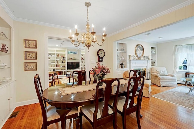 28 Rose Ave, Great Neck, NY 11021 - dining area featuring light wood-type flooring, ornamental molding, built in features, a chandelier, and a fireplace