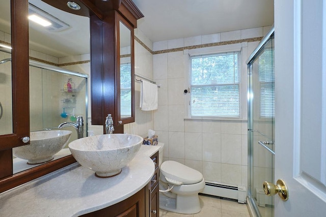 28 Rose Ave, Great Neck, NY 11021 - bathroom with baseboard heating, tile walls, double vanity, a stall shower, and toilet