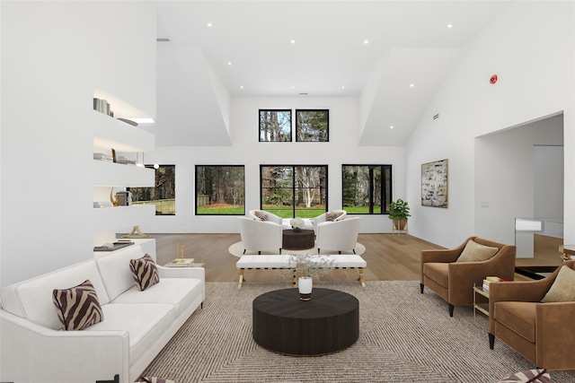 living room with recessed lighting, wood finished floors, and a towering ceiling