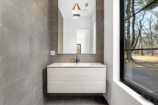bathroom featuring tile patterned flooring, vanity, visible vents, and tile walls