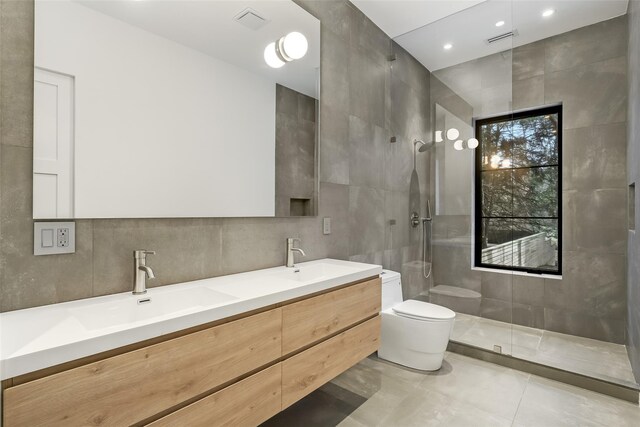 full bathroom with a sink, toilet, tile walls, visible vents, and a walk in shower