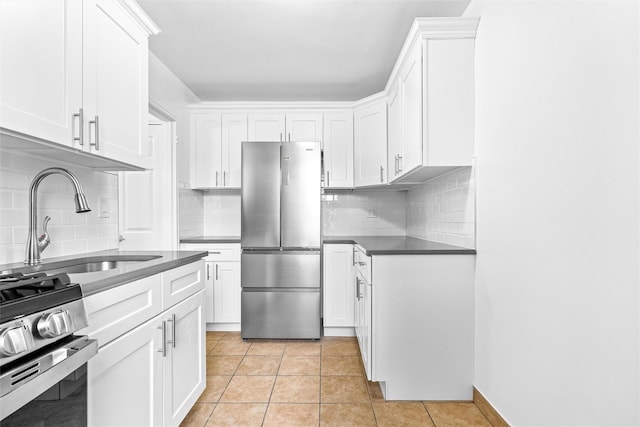 kitchen with white cabinets, stainless steel appliances, a sink, dark countertops, and decorative backsplash