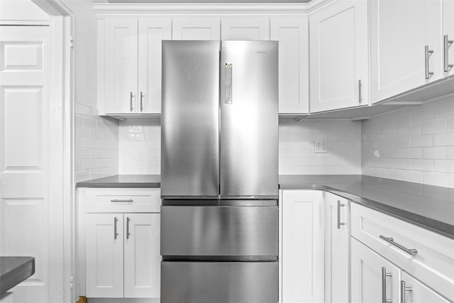 kitchen with dark countertops, freestanding refrigerator, and decorative backsplash