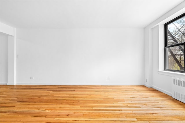 unfurnished room featuring radiator heating unit, wood finished floors, and baseboards