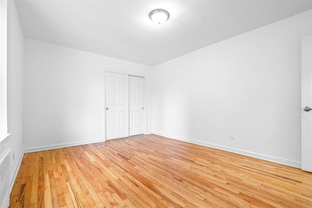 unfurnished bedroom featuring light wood-style floors, baseboards, and a closet