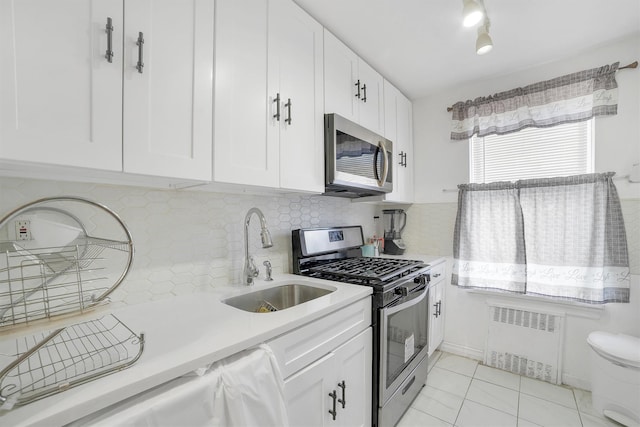 2750 Olinville Ave Unit 1K, Bronx, NY 10467 - kitchen featuring appliances with stainless steel finishes, radiator heating unit, a sink, and white cabinets