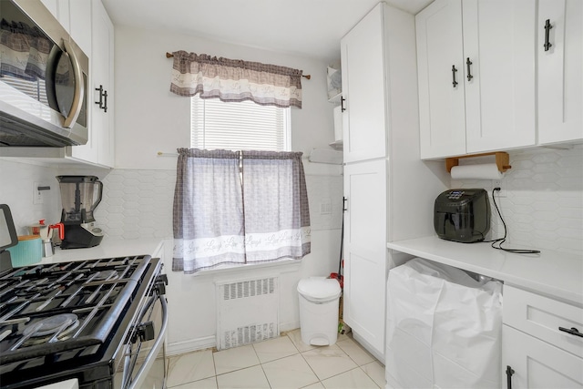 2750 Olinville Ave Unit 1K, Bronx, NY 10467 - kitchen with white cabinets, light countertops, stainless steel microwave, and radiator