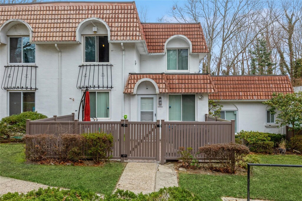 mediterranean / spanish-style home with a tile roof, a gate, and stucco siding