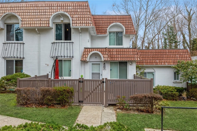 mediterranean / spanish-style home with a tile roof, a gate, and stucco siding