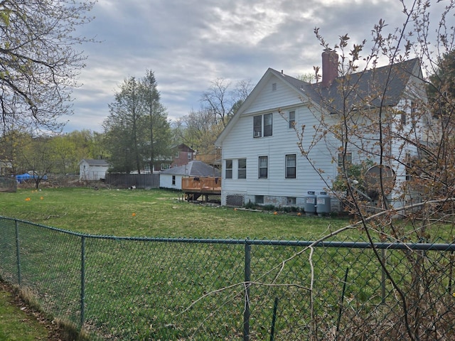 view of home's exterior featuring a deck, a yard, a fenced backyard, and a chimney