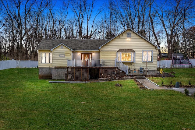 rear view of house featuring a yard, fence, and a deck