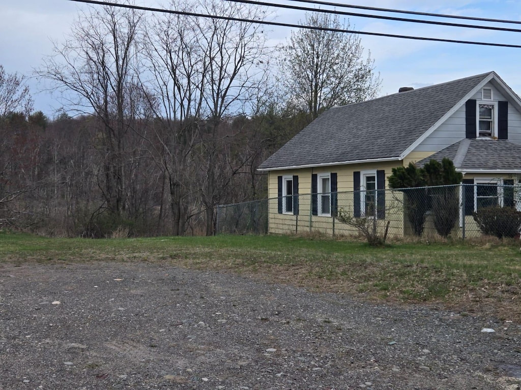 view of front of house with a chimney, fence, and roof with shingles