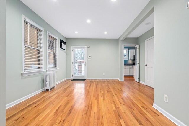 89-21 Aubrey Ave, Glendale, NY 11385 - empty room featuring radiator heating unit, light wood-style floors, a wall unit AC, baseboards, and recessed lighting