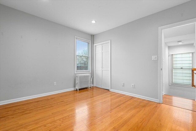 89-21 Aubrey Ave, Glendale, NY 11385 - unfurnished bedroom with radiator heating unit, light wood-style flooring, baseboards, a closet, and recessed lighting