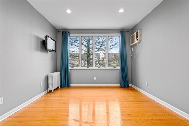 89-21 Aubrey Ave, Glendale, NY 11385 - unfurnished room with radiator heating unit, a wall unit AC, light wood finished floors, recessed lighting, and baseboards