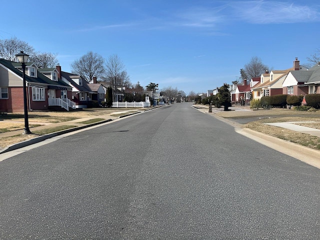 view of road with a residential view, street lighting, curbs, and sidewalks