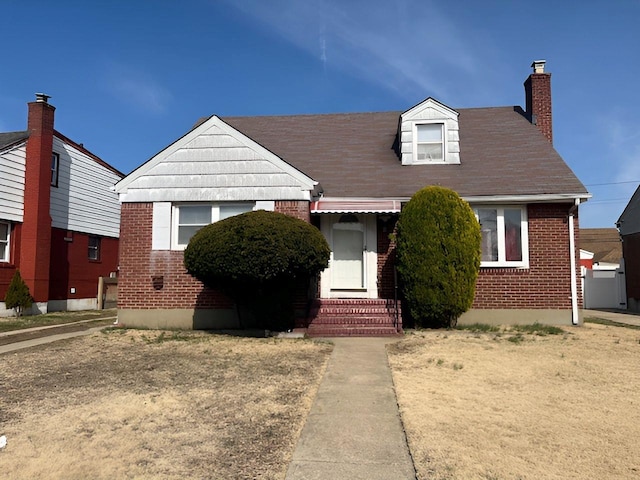 view of front of home with brick siding, a chimney, and entry steps