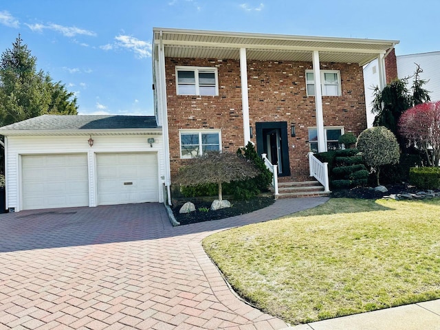 view of front of home featuring brick siding, decorative driveway, a front yard, and a garage