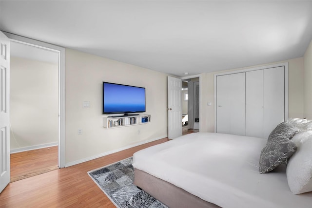 bedroom featuring a closet, baseboards, and wood finished floors