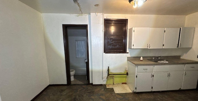 181-10 93rd Ave, Hollis, NY 11423 - kitchen with white cabinetry, baseboards, dark countertops, and a sink