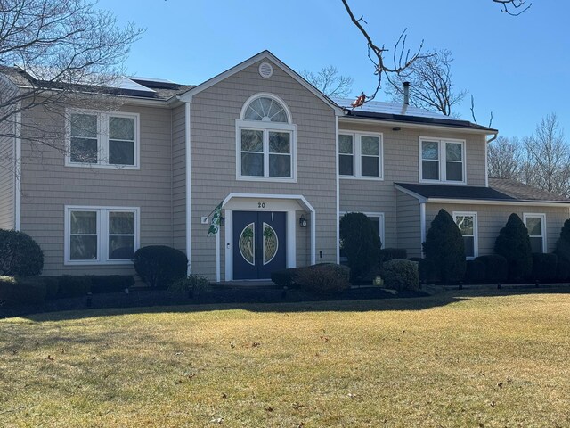 view of front of house featuring solar panels and a front lawn