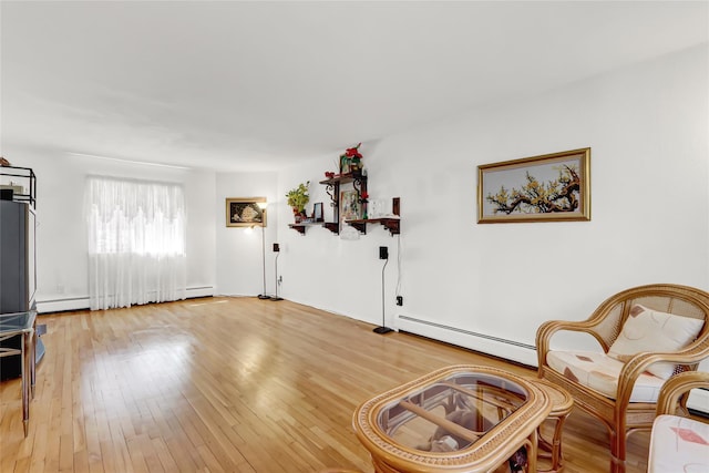 sitting room with a baseboard heating unit and hardwood / wood-style flooring