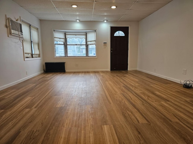 entrance foyer featuring a drop ceiling, baseboards, radiator, and wood finished floors