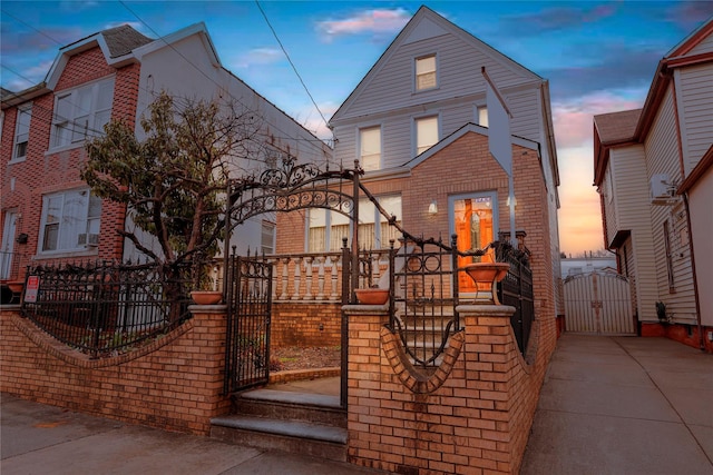 view of front of property with brick siding, a fenced front yard, and a gate