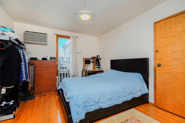bedroom with wood finished floors and a wall mounted AC