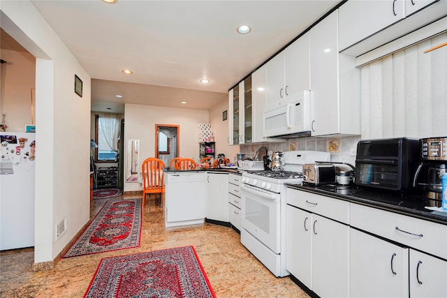 kitchen featuring dark countertops, white cabinets, white appliances, and a peninsula