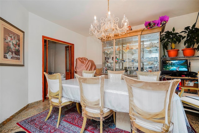 dining space featuring a chandelier and baseboards