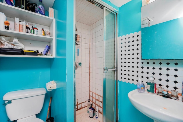 full bathroom featuring a sink, toilet, and a shower stall